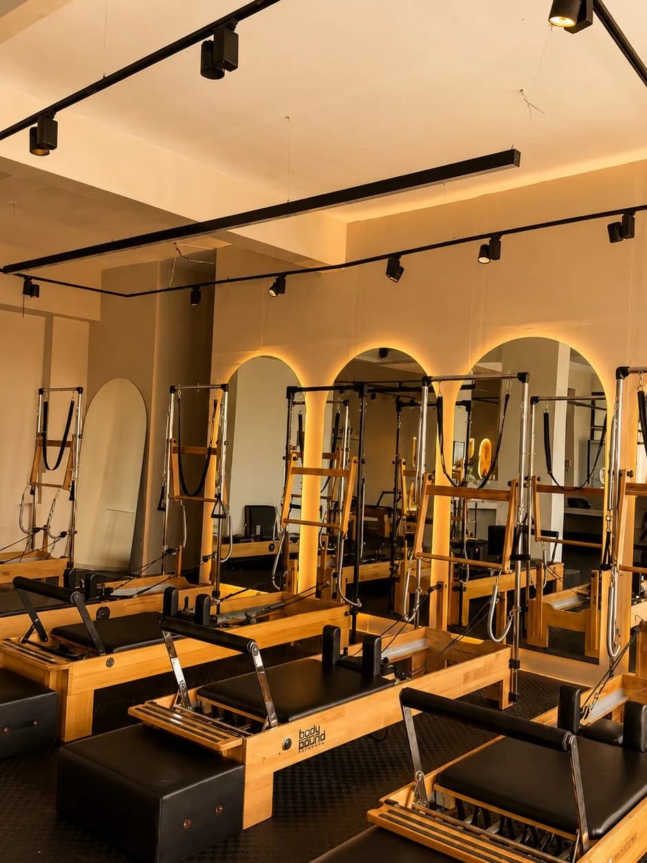GG Studio reformer pilates odası — kemer aynalar ve amber ışıklandırma ile reformer dizilimi
